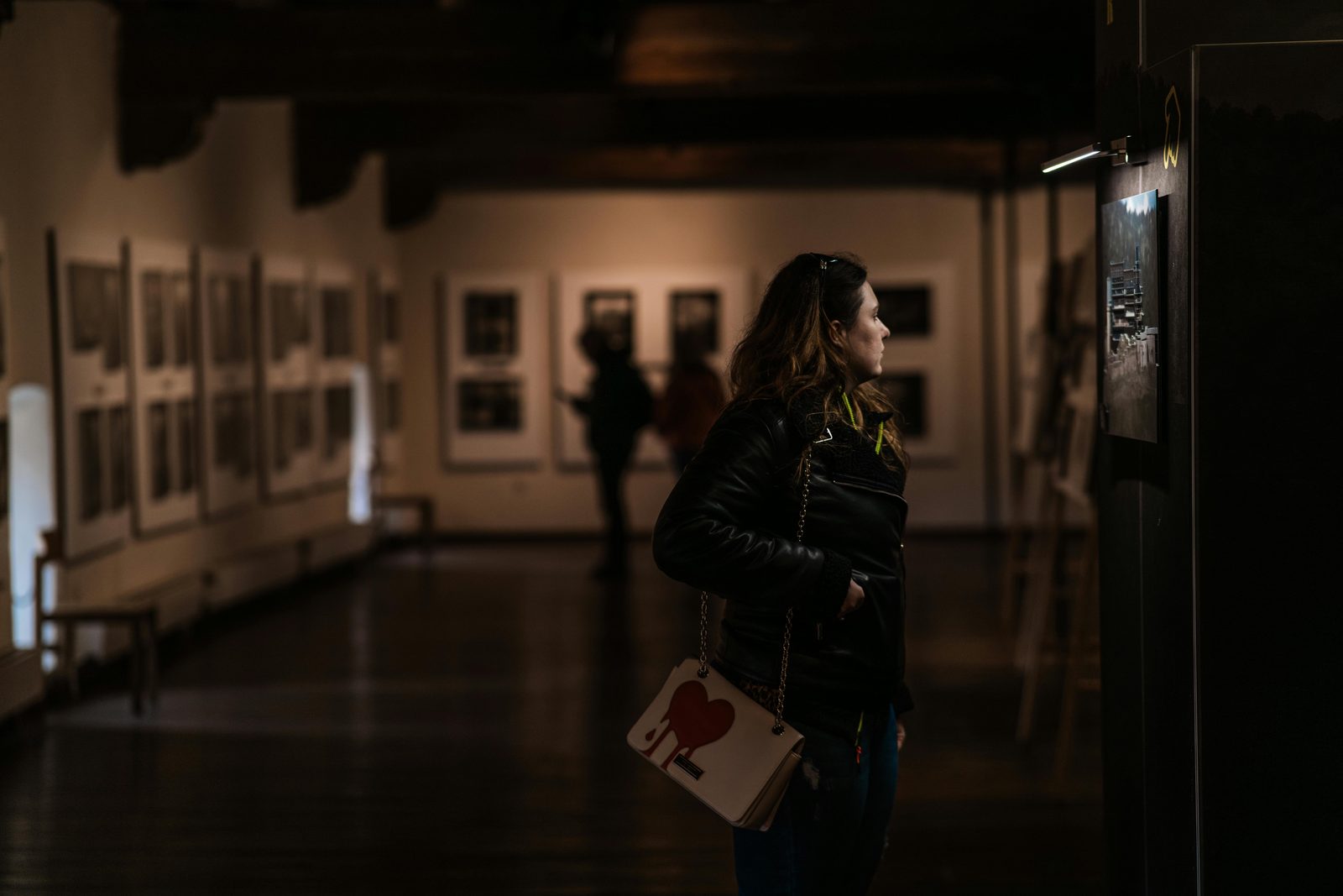 A woman admires artworks in a dimly lit museum gallery — Copenhagen's Culture Night opens 500+ venues from 18:00 to midnight every October for one of Europe's largest cultural events