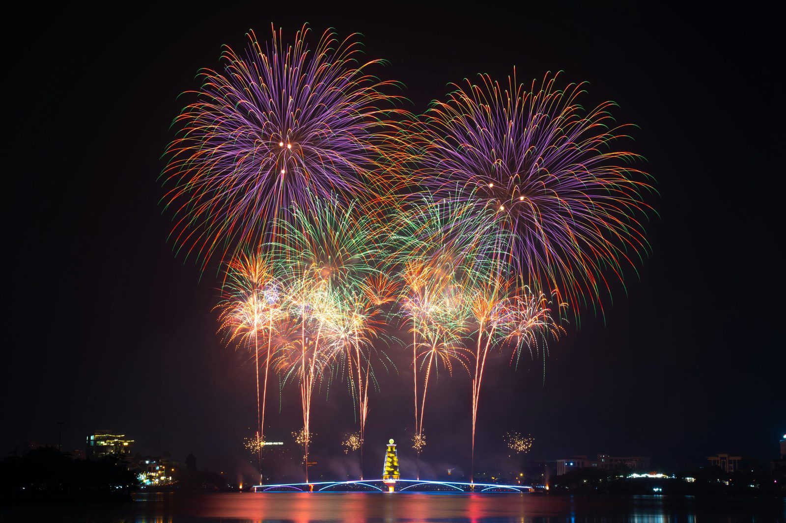 Colorful fireworks explode magnificently over a cityscape — New Year's Eve in Copenhagen peaks at midnight over the harbour and Tivoli with private fireworks across every neighbourhood