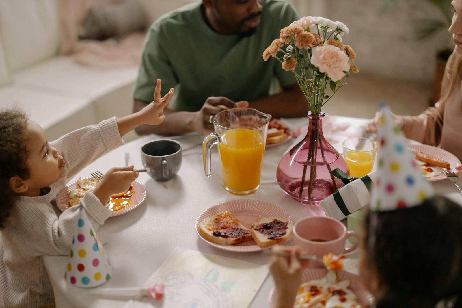 Family having a cheerful meal together with small children — similar to Copenhagen's child-friendly cafés Absalon, Mad & Kaffe and Aamanns