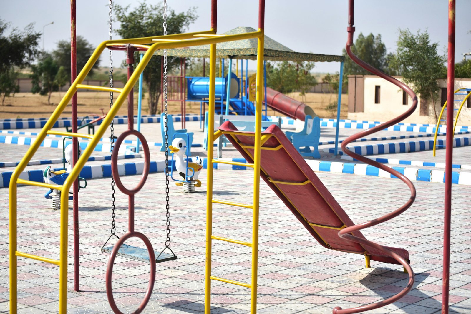 Colorful outdoor playground with slides and swings — similar to the free public playgrounds in Copenhagen's Kongens Have, Fælledparken and Superkilen