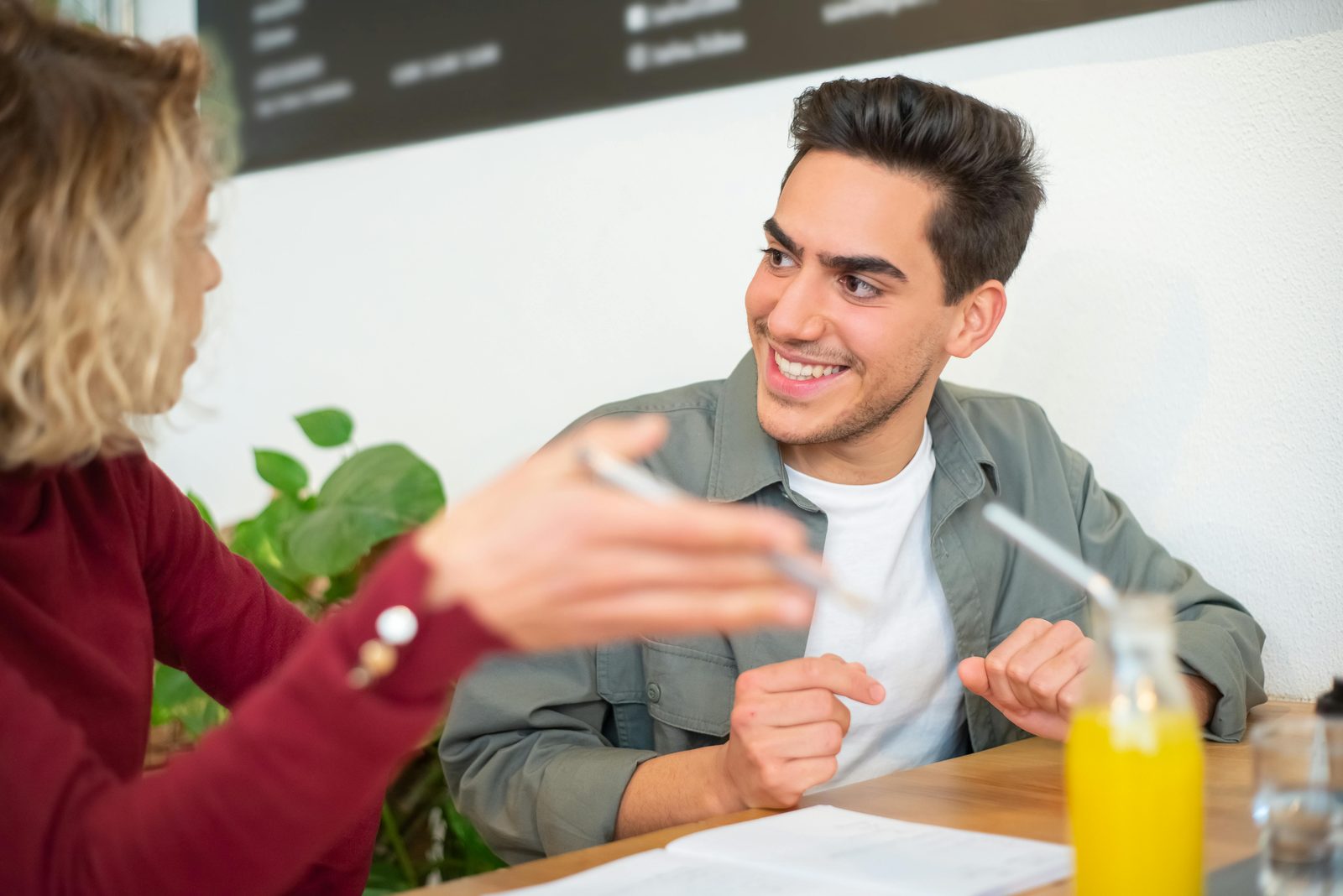 Two young adults in a positive conversation in a cozy café — 86% of Danes speak English fluently, so Copenhagen is one of Europe's easiest cities to navigate