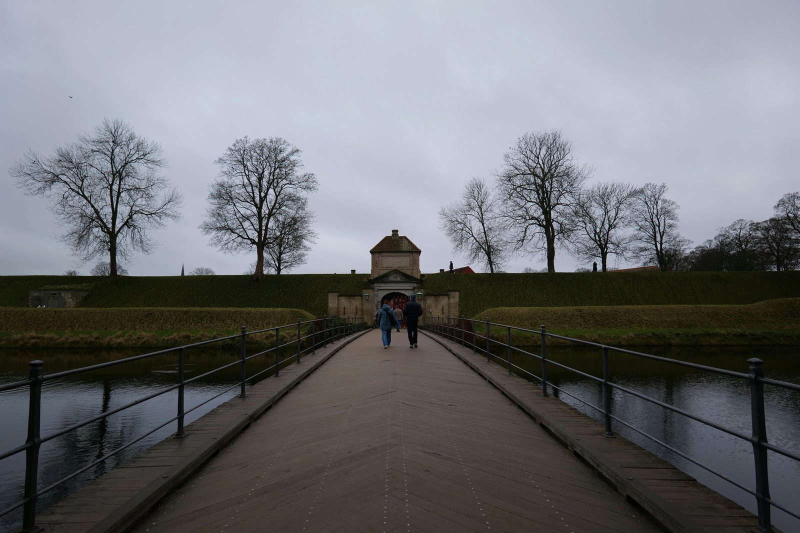 Visitors walking across the bridge to a historic fort entrance — Copenhagen's star-shaped Kastellet fortress sits 200 metres south of the Little Mermaid statue