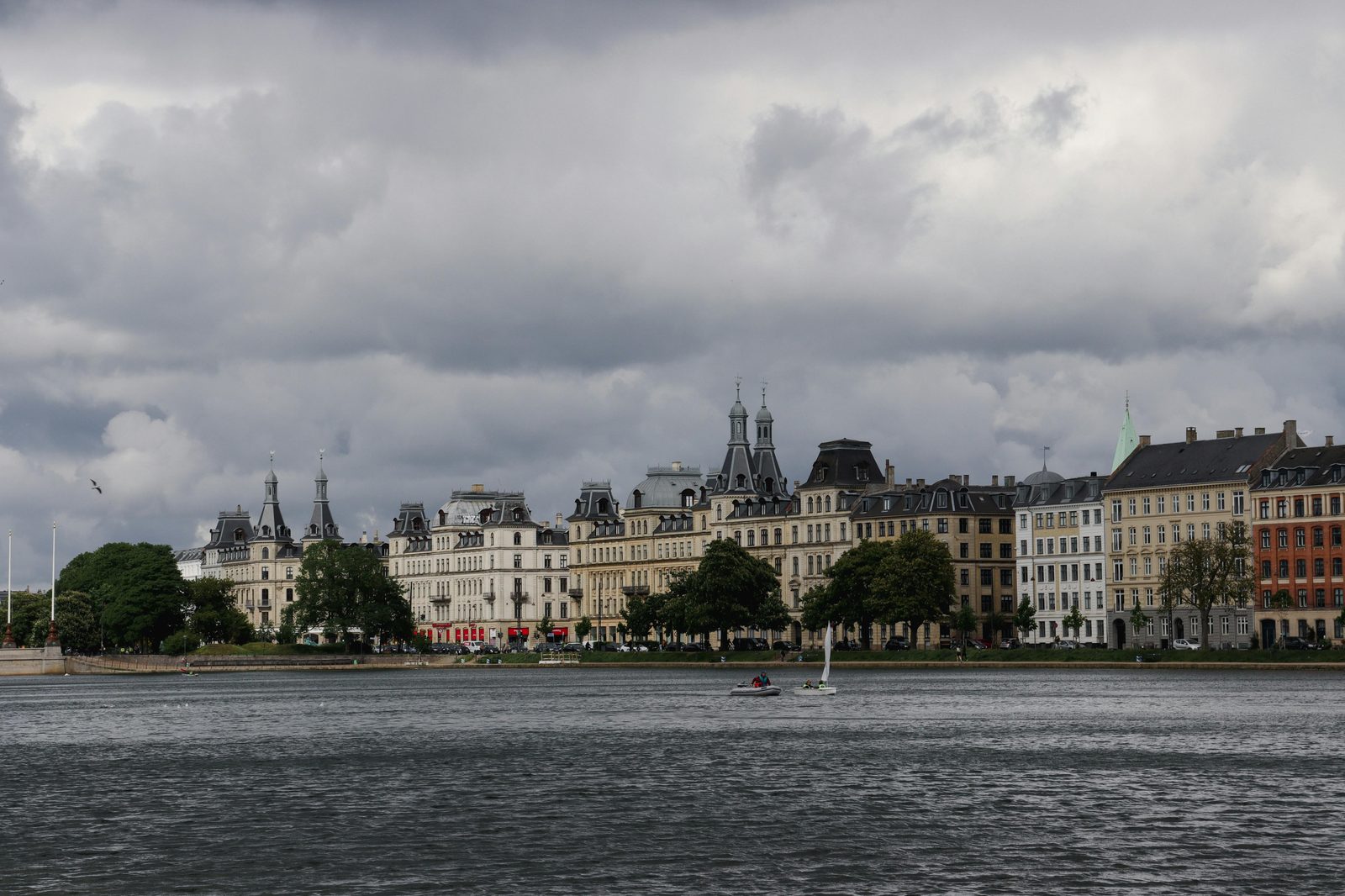 Dramatic clouds over classic Copenhagen architecture by the waterfront — the Little Mermaid statue sits on Langelinie quay, a 30-minute walk north of Nyhavn
