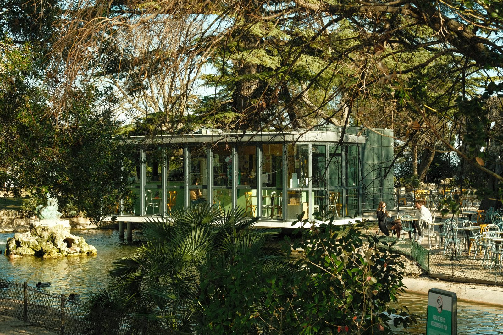 A serene café terrace overlooking a pond with trees and sunlight — the Glyptotek's café in the Winter Garden is one of Copenhagen's most beautiful coffee spots