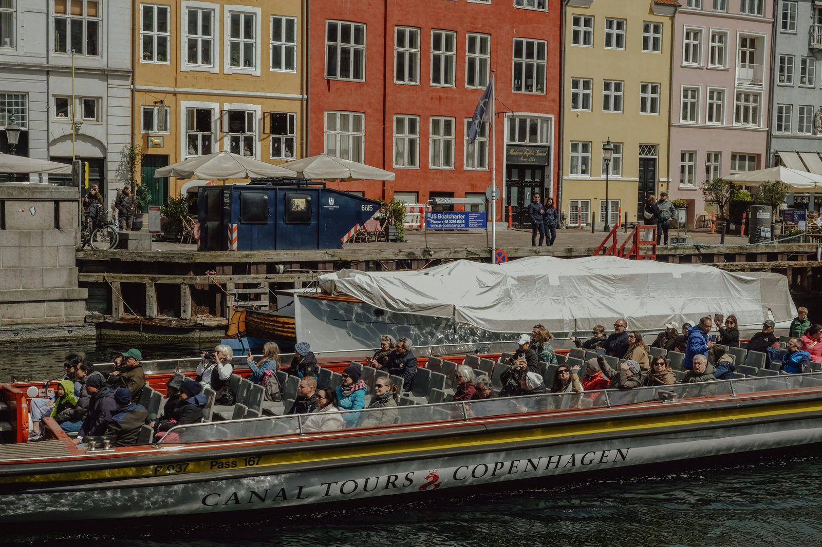 Tourists enjoying a scenic canal tour boat in Copenhagen, Denmark, with vibrant waterfront — Nyhavn is the main departure point for Copenhagen's canal tours