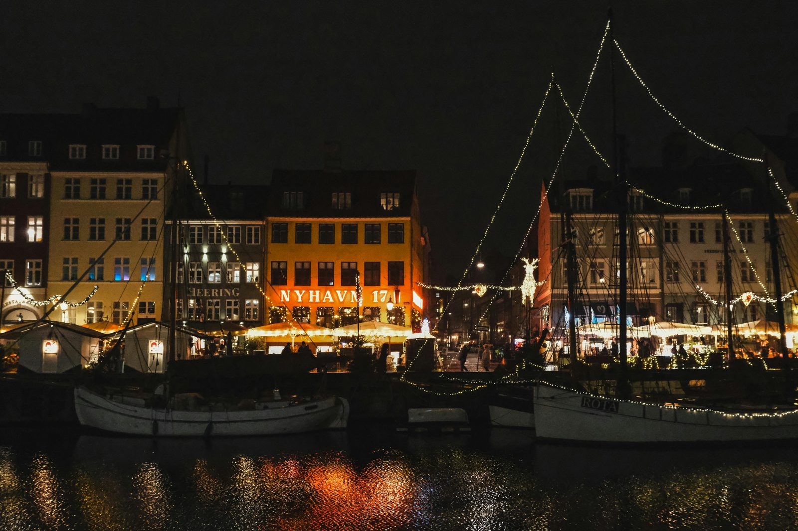 Captivating night scene of Nyhavn Copenhagen with festive Christmas lights reflecting on the water — Nyhavn hosts Copenhagen's most atmospheric Christmas market