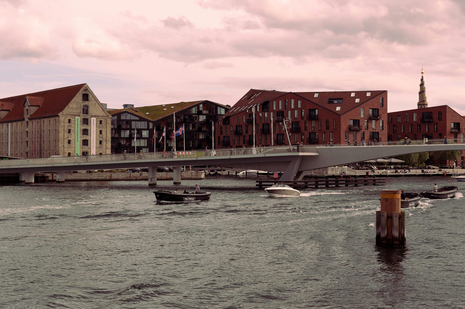 Scenic view of Inderhavnsbroen bridge and waterfront buildings in Copenhagen at dusk — the 'Kissing Bridge' connects Nyhavn directly to Christianshavn