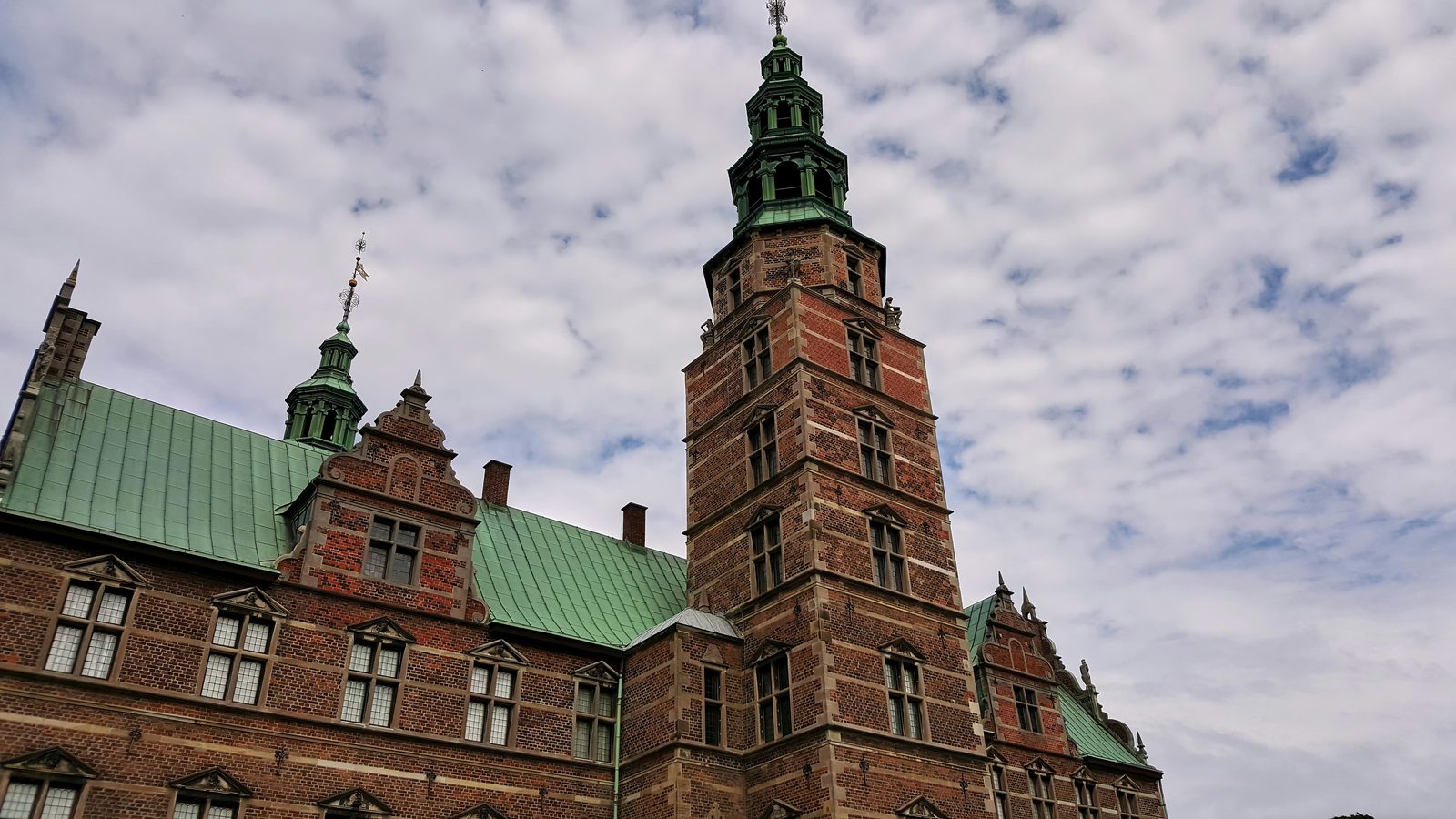 Majestic view of Rosenborg Castle showcasing stunning Renaissance architecture under a bright sky — three towers, copper roofs, red brick and sandstone