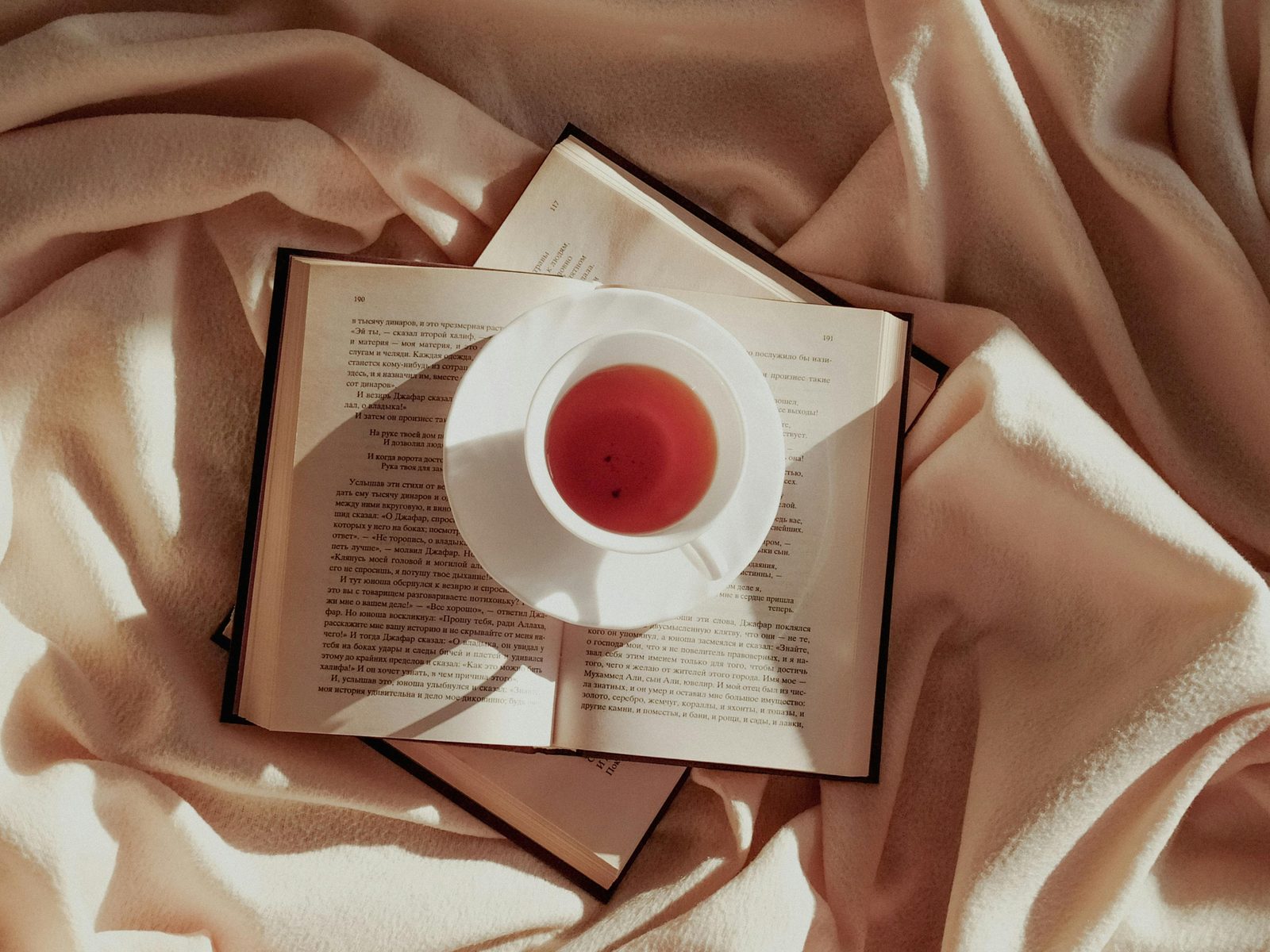 Blanket tea cup cozy reading — hygge essentials include blankets, hot drinks, soft lighting, and unhurried time