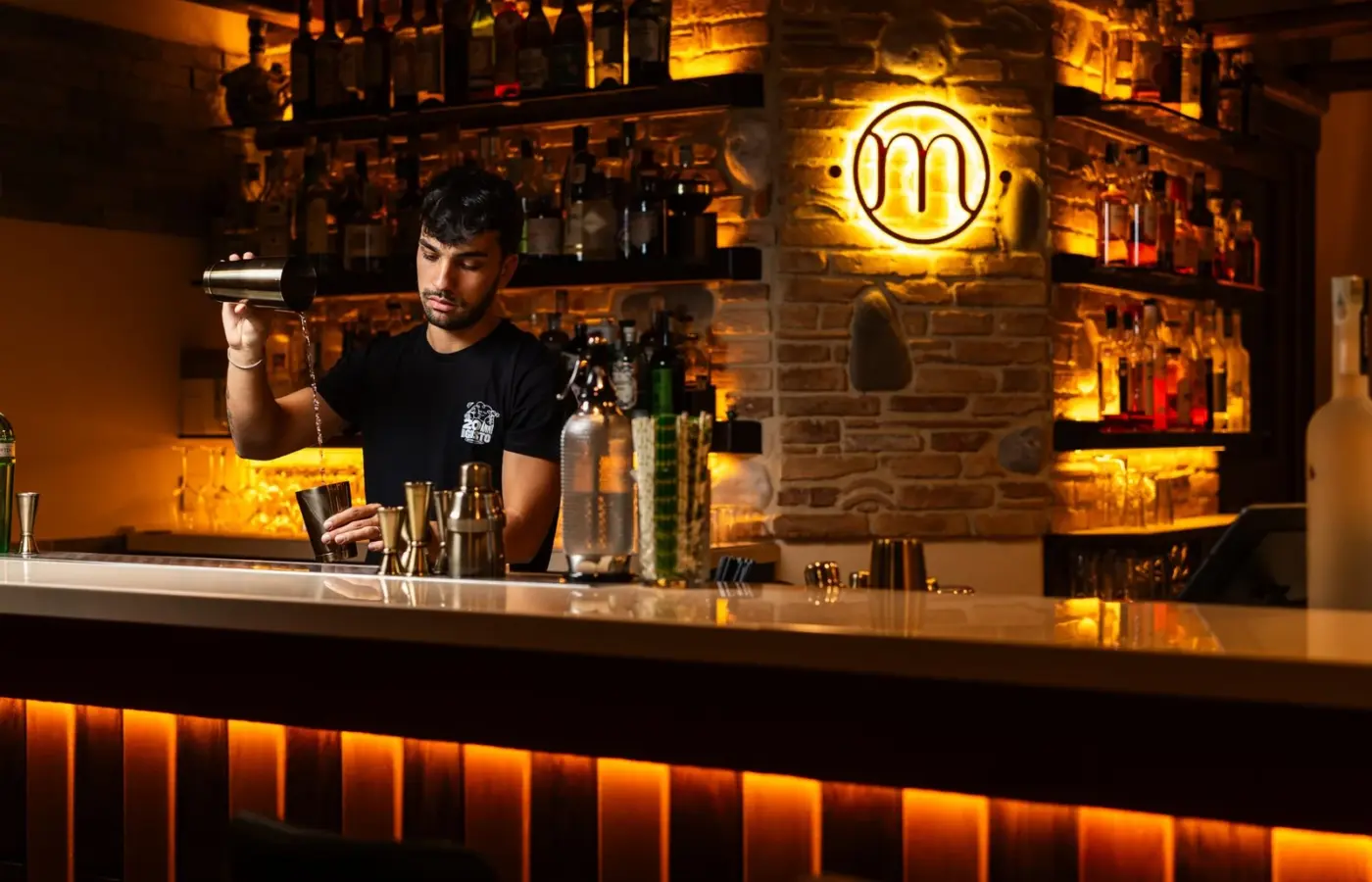 A bartender mixing a drink in a dimly lit cocktail bar