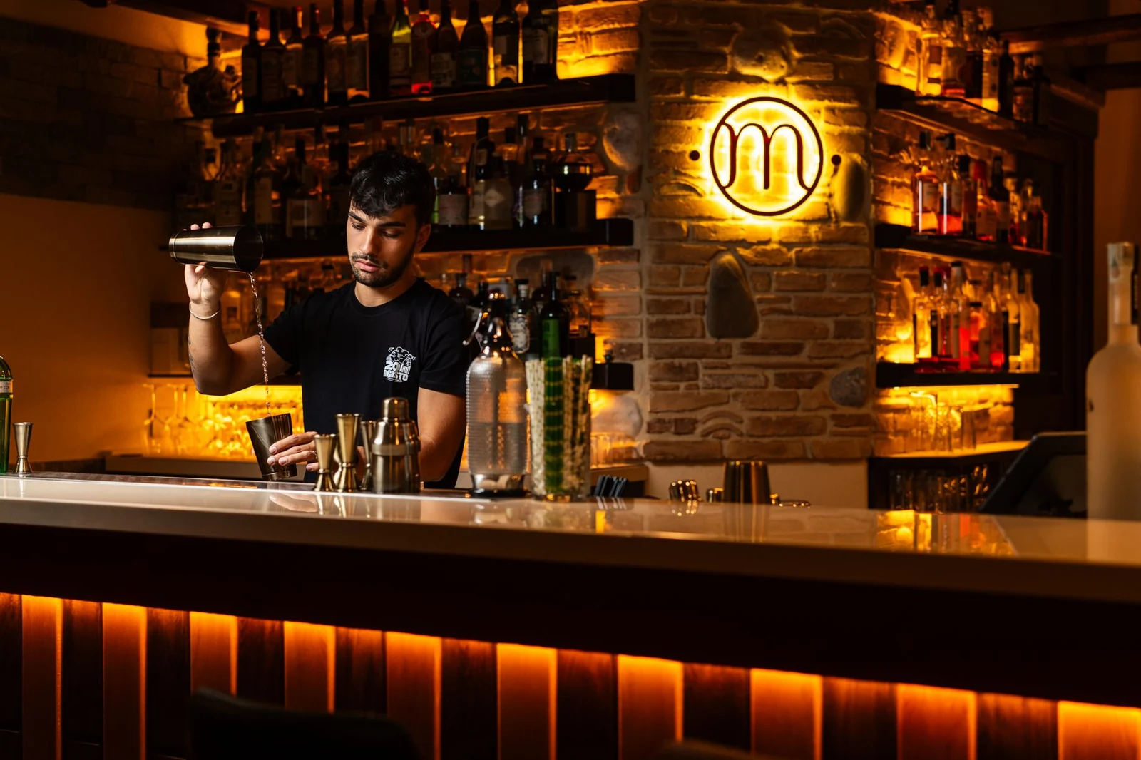 A bartender mixing a drink in a dimly lit cocktail bar