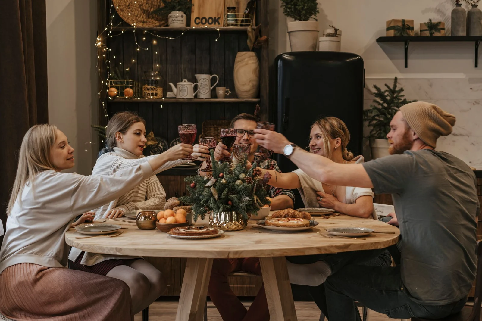 Friends around a home dinner table raising glasses in a toast and looking at each other