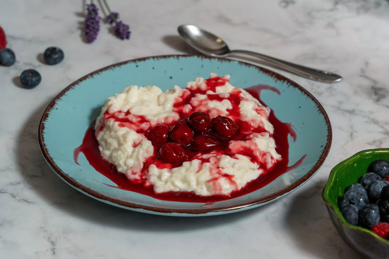 Rice pudding topped with warm cherry sauce on a pale blue plate