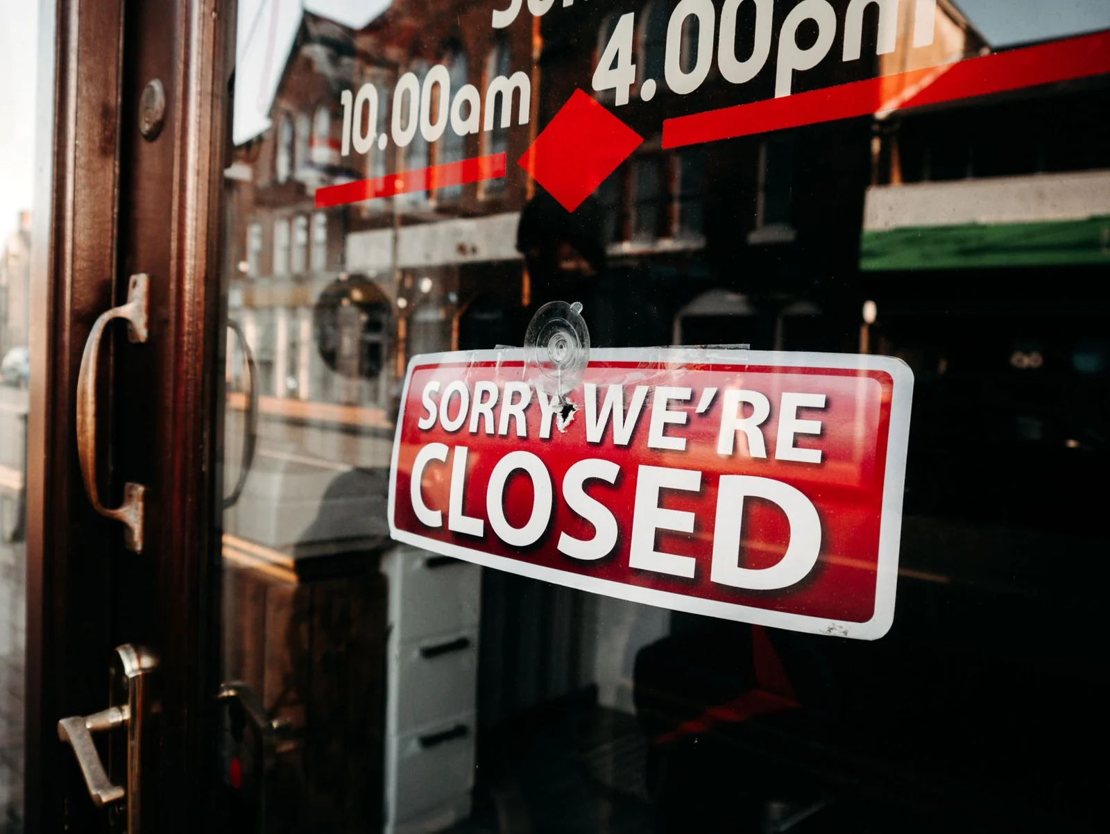 A red closed sign hanging on the glass door of a shop