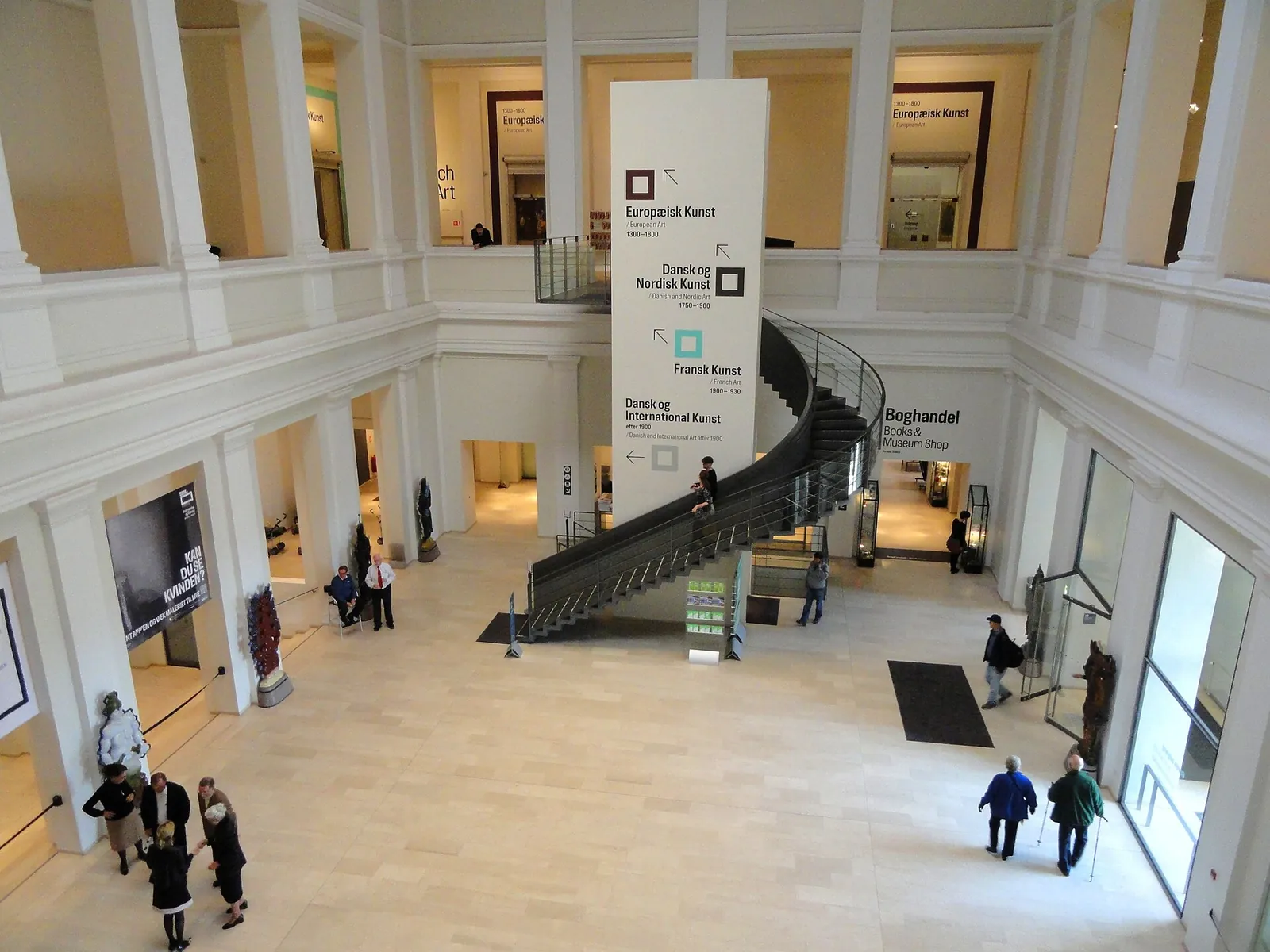 The entrance hall of SMK with its suspended staircase and signs pointing to the collections