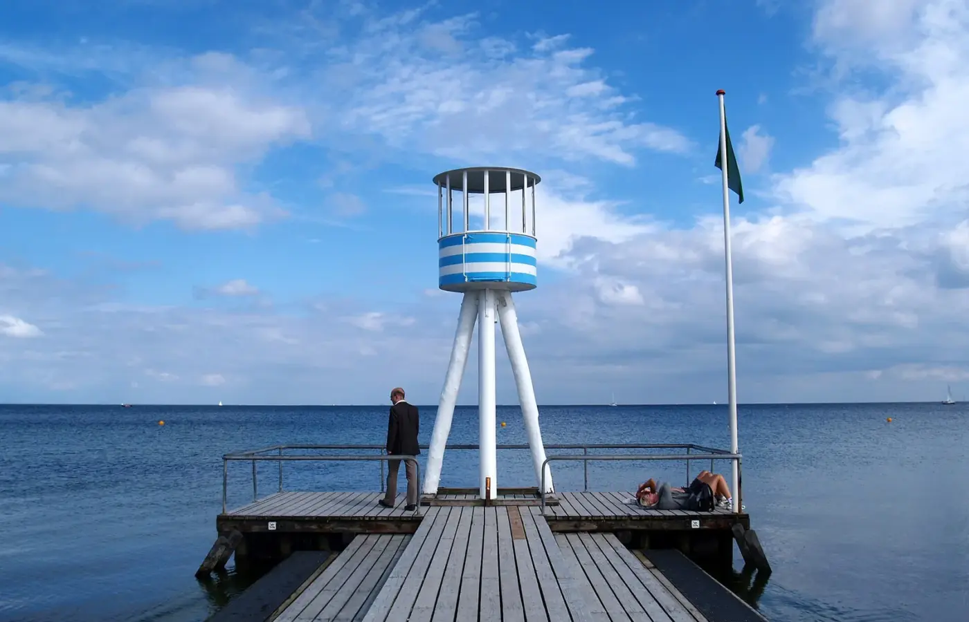 Arne Jacobsen's blue-and-white striped lifeguard tower on a wooden pier at Bellevue beach, Klampenborg