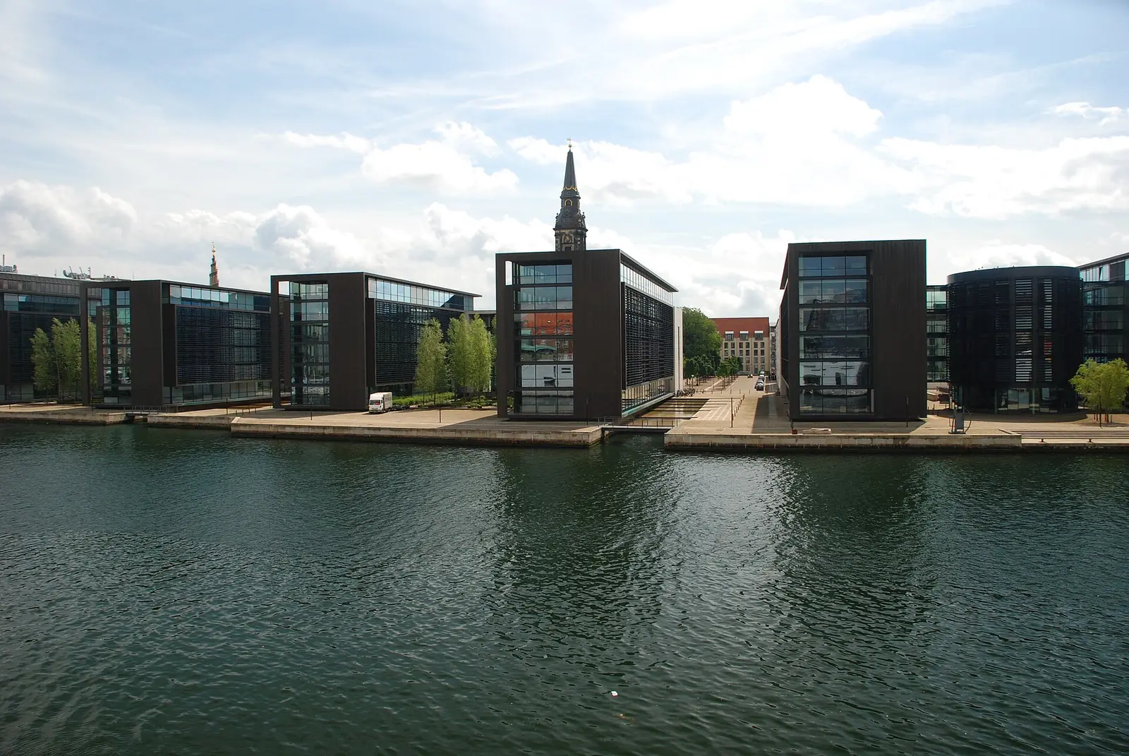 Modern office blocks on the Christianshavn waterfront with a church spire behind