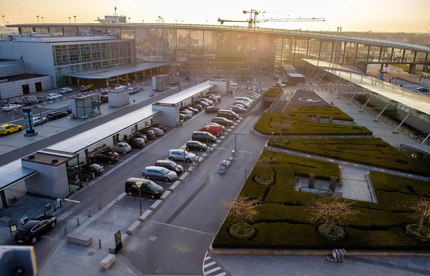 Copenhagen Airport Terminal 3 seen from above at sunset, with the taxi rank, drop-off lanes and gardens in front