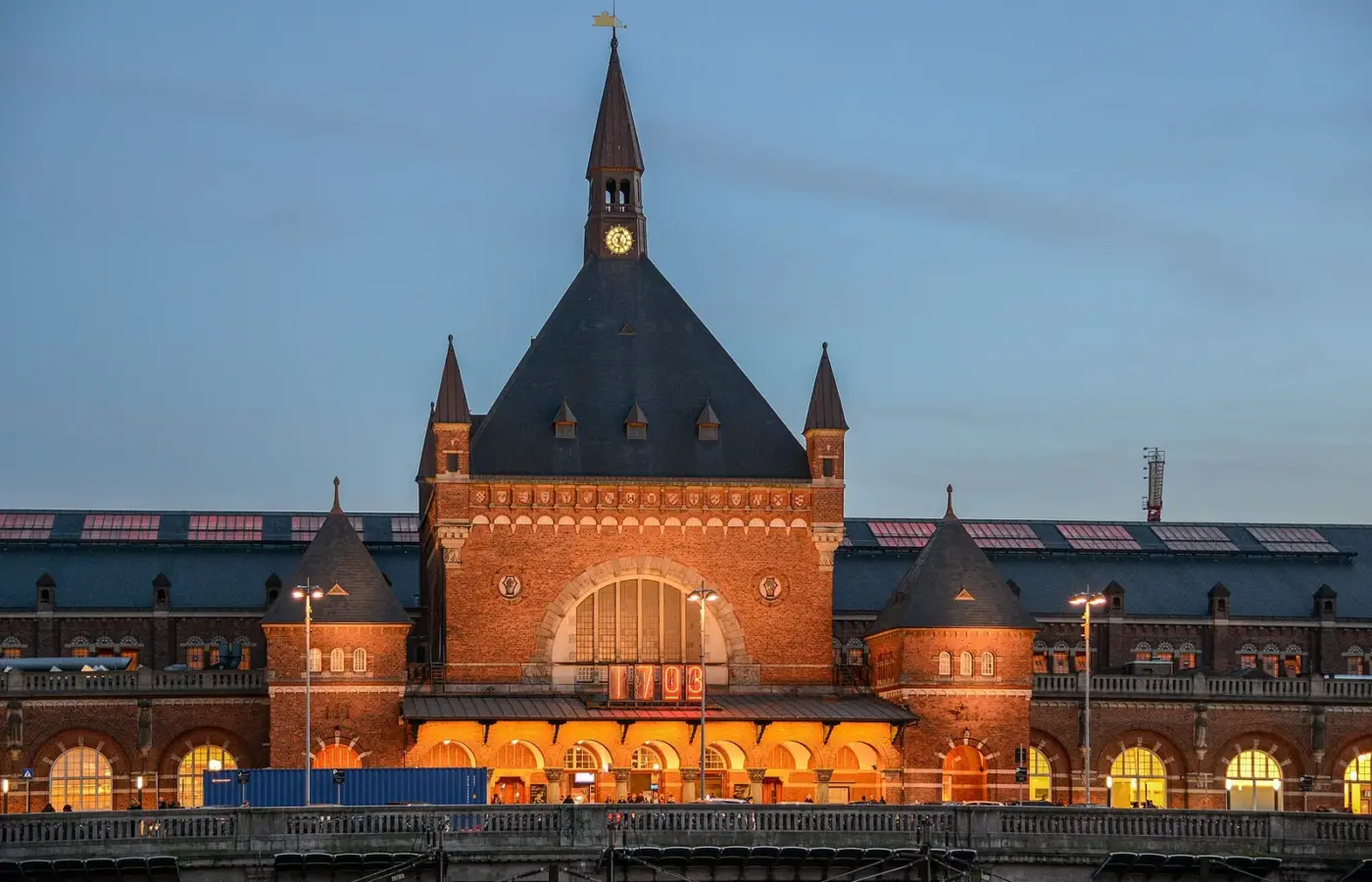 The red-brick facade and clock tower of Copenhagen Central Station, Kobenhavns Hovedbanegard, lit up at dusk