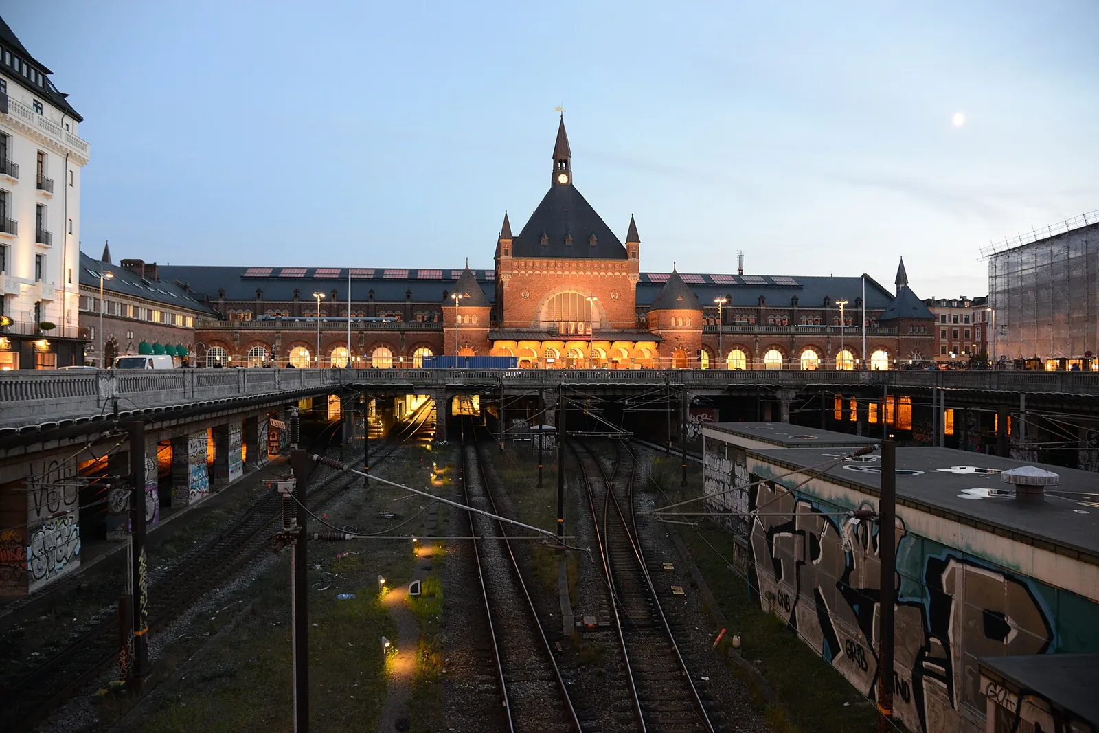 Copenhagen Central Station seen from above the railway tracks at dusk, with the platforms running under the street