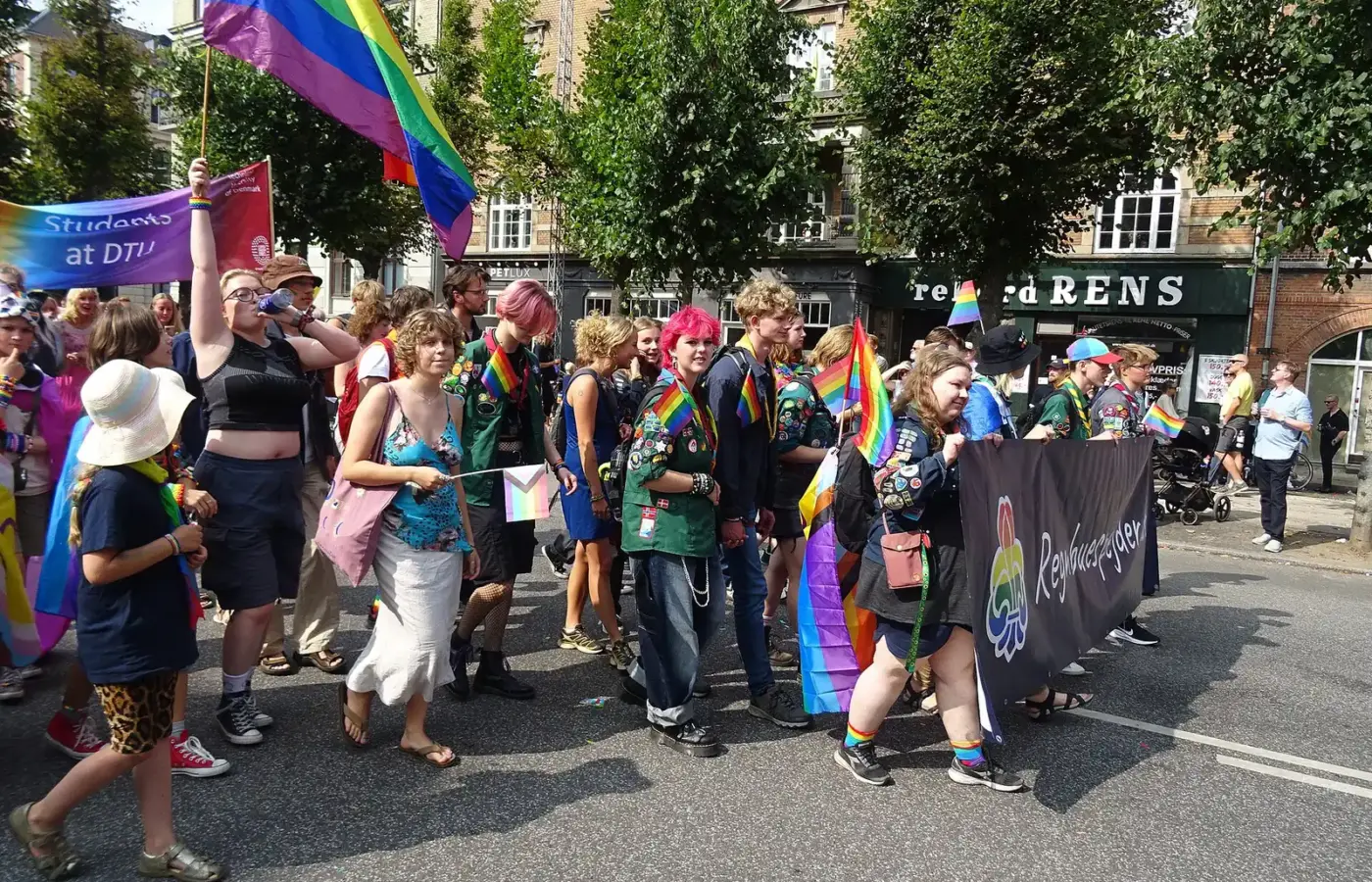 Marchers with rainbow flags and banners in the Copenhagen Pride parade on a sunny August day