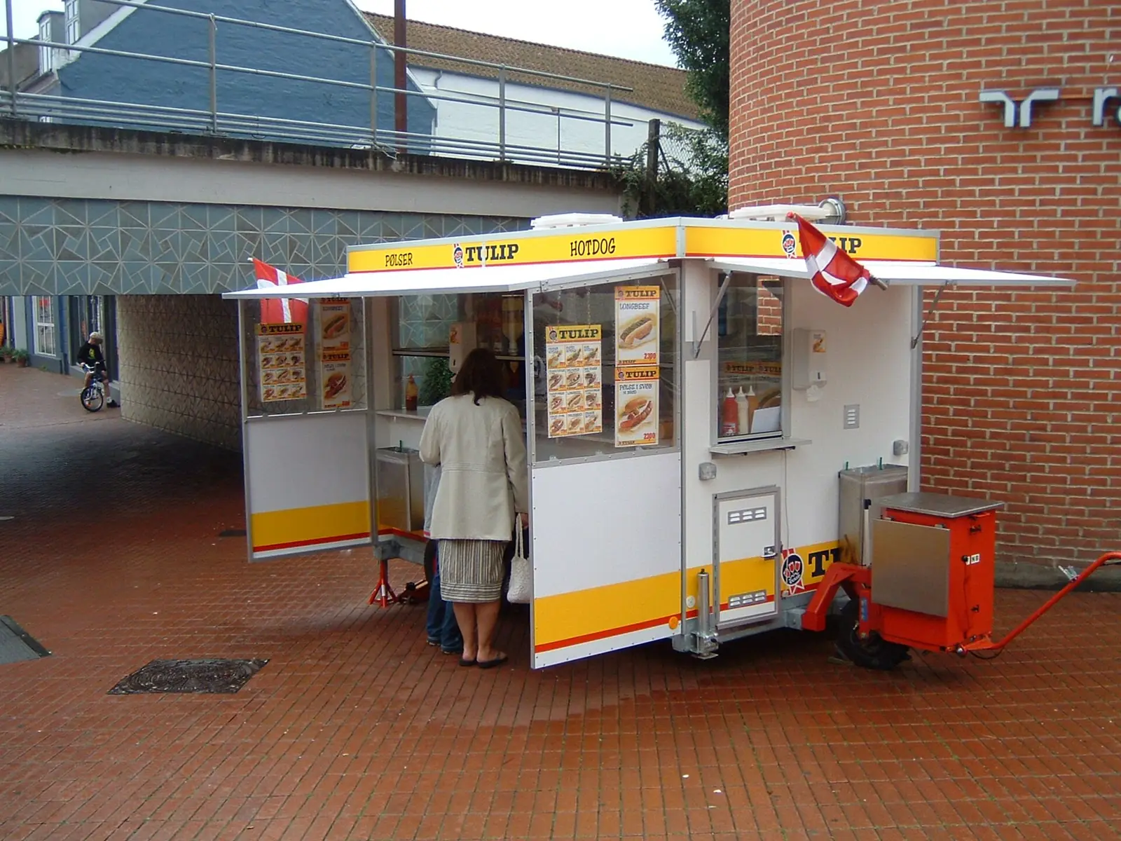 A traditional Danish hot dog wagon with its hatch open, awnings out and menu boards in the windows