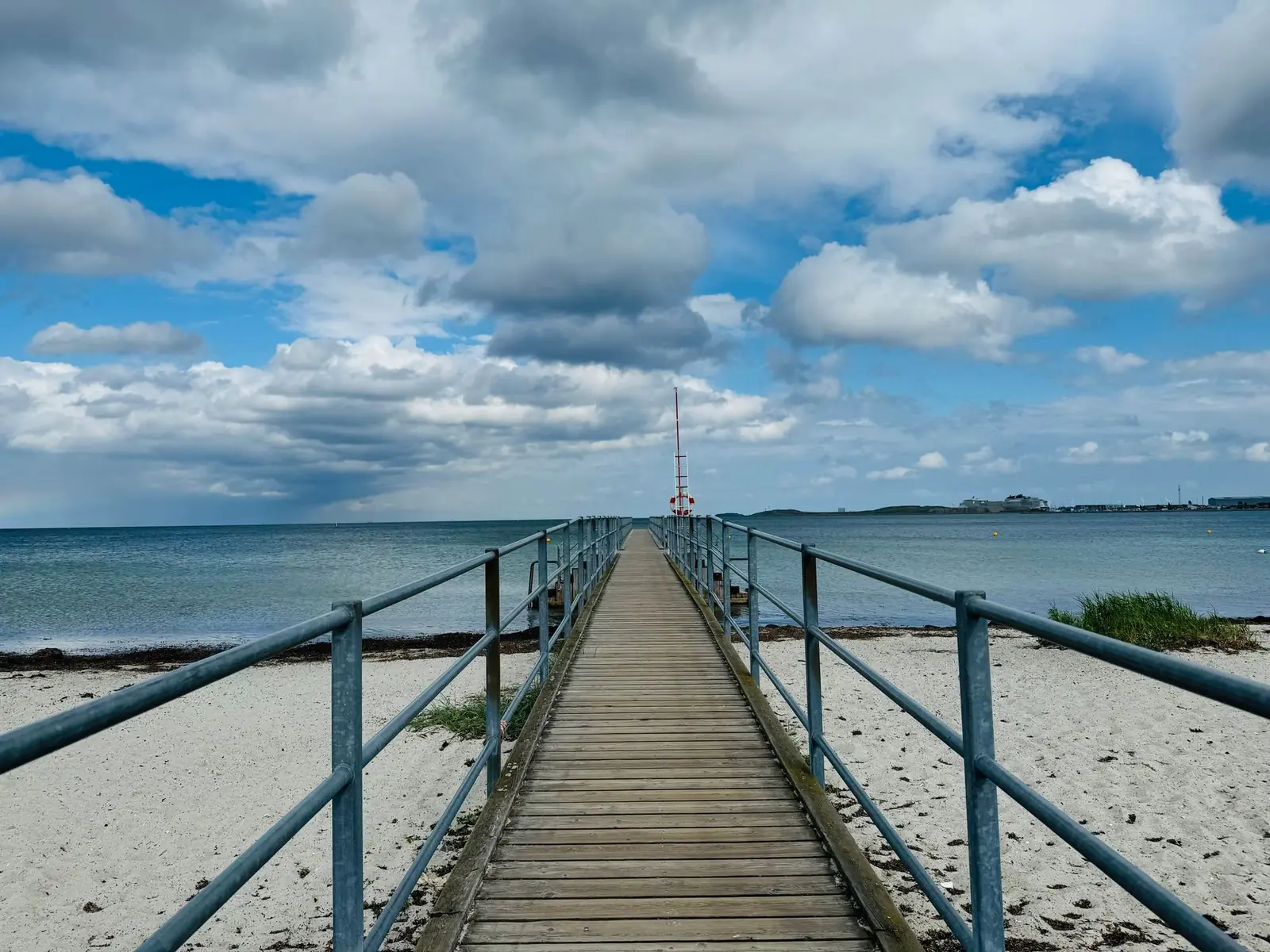 A long wooden bathing pier over a sandy beach on the Oresund coast at Hellerup