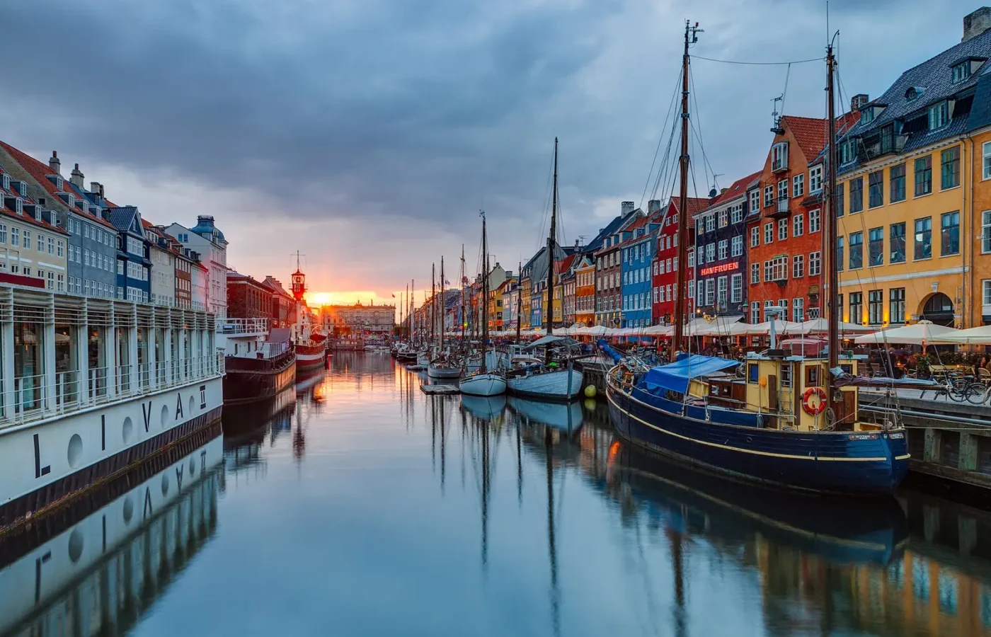 Old wooden boats moored along Nyhavn canal at sunset